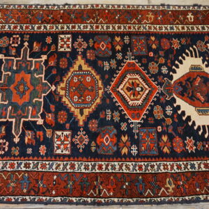 Geometric high-pile runner rug in navy and rust with colorful medallions, displayed on light wood floorboards.