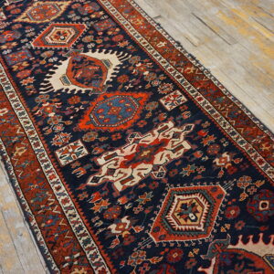 Dark blue runner rug with rust borders and geometric patterns on distressed plank wood flooring.