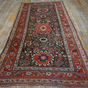 Traditional runner rug with rust borders and dark field motifs rests on distressed, peeling light hardwood flooring.
