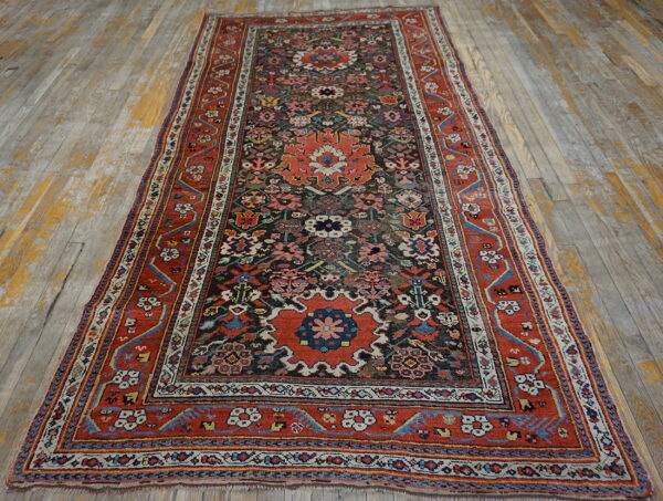 Traditional runner rug with rust borders and dark field motifs rests on distressed, peeling light hardwood flooring.