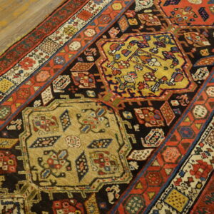 Multicolored traditional rug with detailed yellow, red, and black geometric designs rests on light wood flooring.