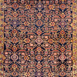 Navy rug with an all-over geometric and floral pattern in red, gold, and blue on wood flooring.