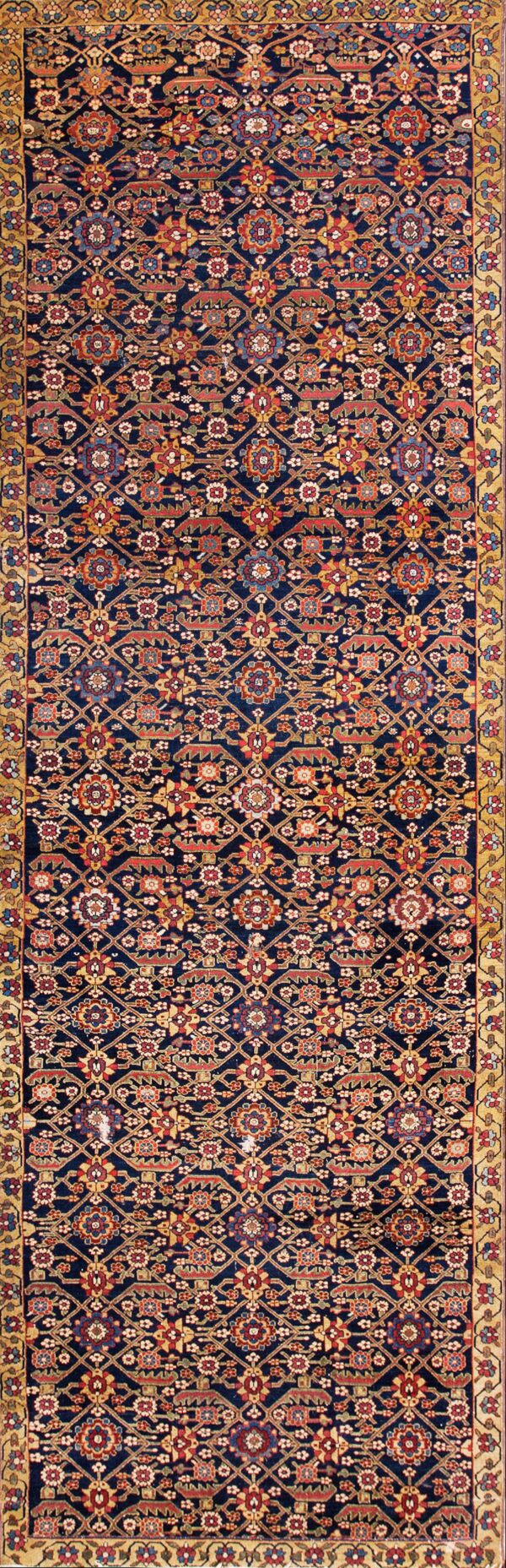 Navy rug with an all-over geometric and floral pattern in red, gold, and blue on wood flooring.