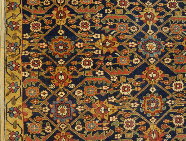 Densely patterned rug featuring a navy field, red and gold motifs, and a wide gold floral border.
