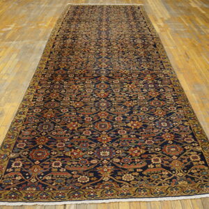 Long dark blue runner rug with dense floral and geometric patterns rests on a golden plank floor.