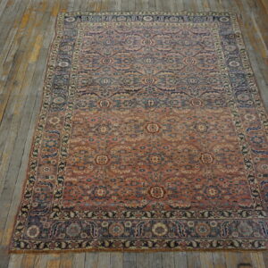 Coral and blue low-pile oriental rug with an intricate floral pattern on distressed gray wood planks.