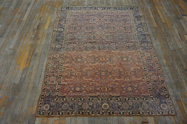 Coral and blue low-pile oriental rug with an intricate floral pattern on distressed gray wood planks.