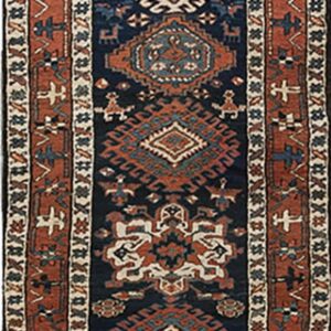 Geometric tribal runner rug featuring stepped medallions on a navy blue field with rust borders.