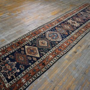 Navy and rust geometric runner rug featuring central medallions on weathered wooden planks.