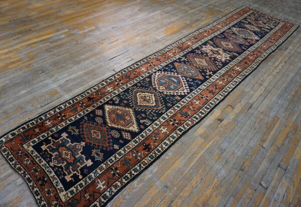 Navy and rust geometric runner rug featuring central medallions on weathered wooden planks.