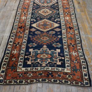 Navy and rust geometric runner rug with tribal medallions on distressed wood plank flooring.