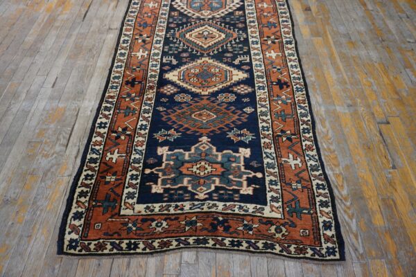 Navy and rust geometric runner rug with tribal medallions on distressed wood plank flooring.