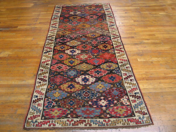 A long runner rug featuring colorful geometric floral motifs on a dark ground, lying on hardwood flooring.