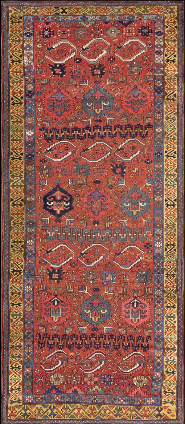 Geometric runner rug with a brick red field, diverse motifs, and intricate yellow and blue borders.