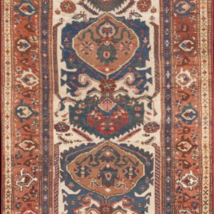Low-pile runner rug displaying a tribal geometric pattern in distressed rust, blue, and light beige.