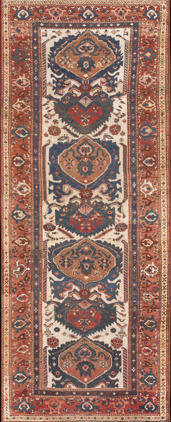 Low-pile runner rug displaying a tribal geometric pattern in distressed rust, blue, and light beige.