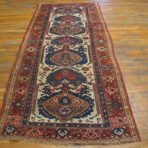 Geometric runner rug in shades of red, blue, and cream, lying across worn wood plank flooring.