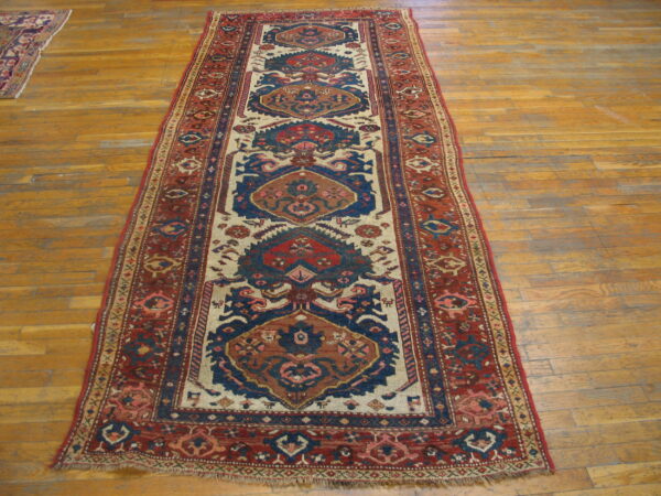 Geometric runner rug in shades of red, blue, and cream, lying across worn wood plank flooring.