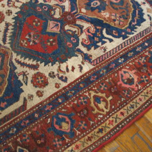 Traditional rug with complex red, blue, and cream borders and medallions resting on yellow parquet floor.