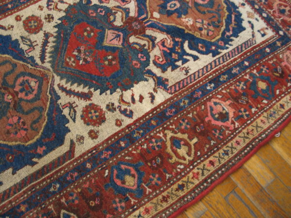 Traditional rug with complex red, blue, and cream borders and medallions resting on yellow parquet floor.