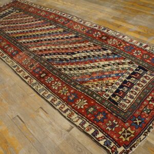 Multi-colored runner with rust borders and diagonal striped geometric patterns rests on distressed wood planks.
