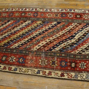 Multicolor low-pile runner featuring diagonal geometric stripes and red borders on light wood flooring.