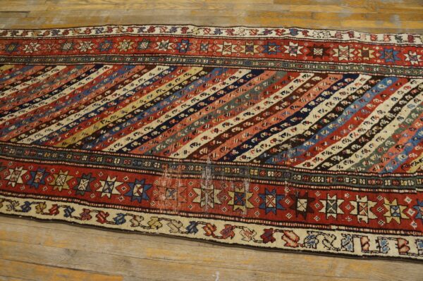 Multicolor low-pile runner featuring diagonal geometric stripes and red borders on light wood flooring.