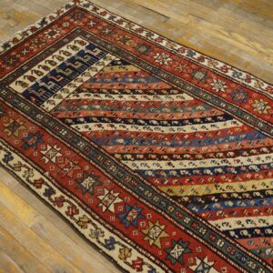 Multi-colored tribal runner rug featuring diagonal stripes and complex geometric motifs on worn wooden floors.