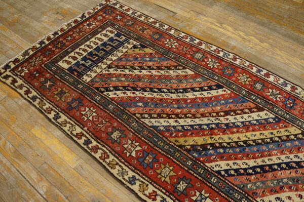 Multi-colored tribal runner rug featuring diagonal stripes and complex geometric motifs on worn wooden floors.