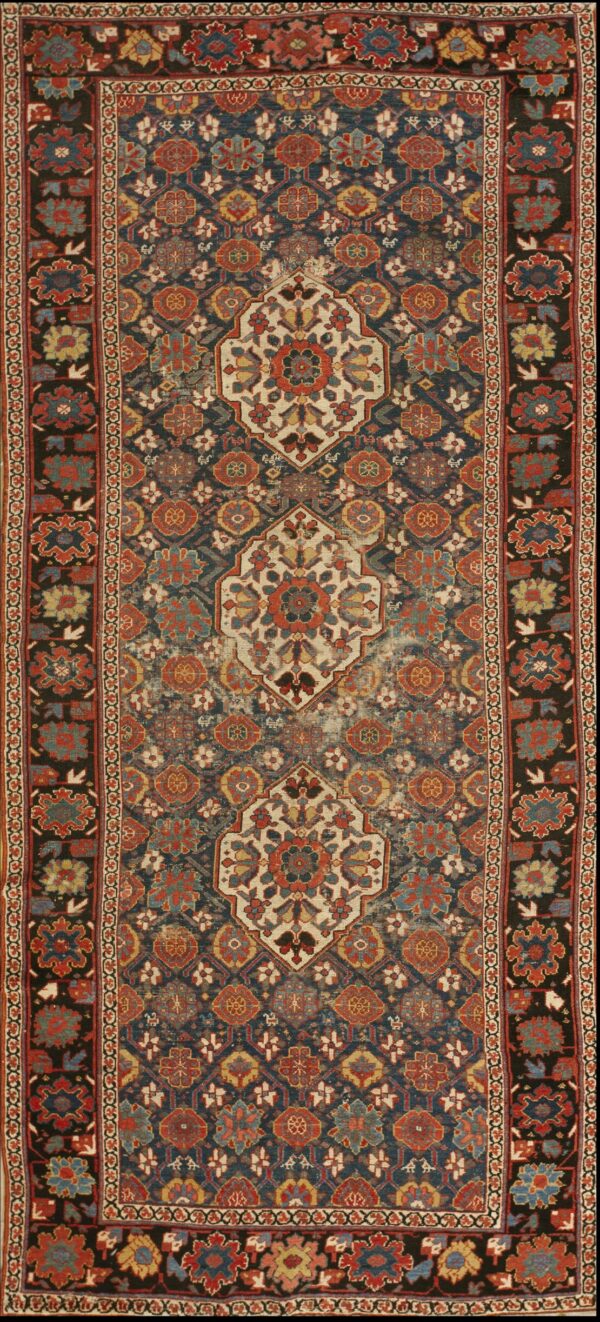 Ornate traditional rug featuring a dark blue field, terracotta motifs, and three cream central medallions with dark borders.