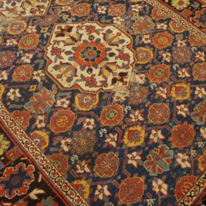 Distressed rug with navy, red, and cream geometric motifs on a light wood floor.