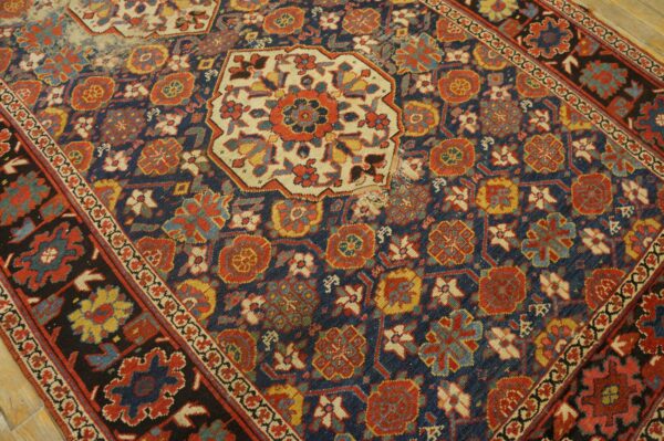 Distressed rug with navy, red, and cream geometric motifs on a light wood floor.