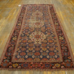 Runner rug featuring intricate medallions in red, blue, and cream on distressed wooden floor planks.
