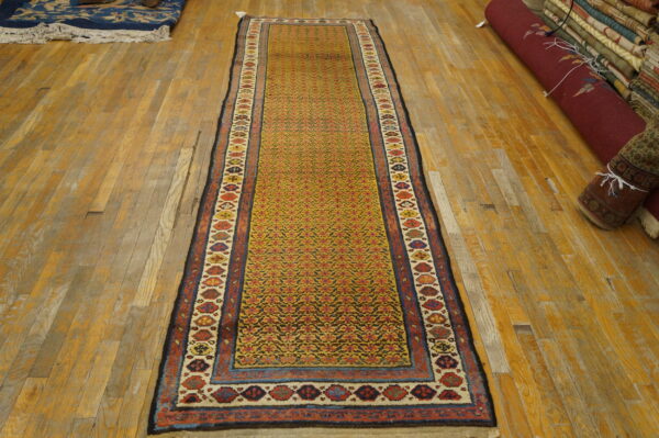 Yellow-gold geometric runner with intricate red and blue patterns, laid on distressed wood planks.