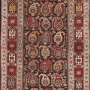 A narrow runner rug with a dark field and repeating red, cream, and blue stylized paisley motifs.