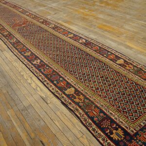 Navy and red geometric runner rug with wide borders is displayed on rustic light wood flooring.