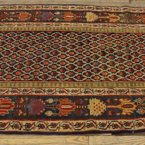 Textured runner rug with a repeating lattice pattern and bold multicolored borders on light wood flooring.