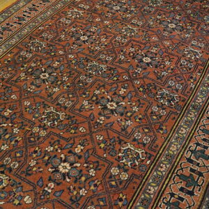 Burnt orange patterned runner rug with navy and cream motifs lying on light wood flooring.