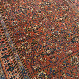 Rust rug featuring a dense floral geometric pattern in blue, cream, and yellow on wood floor.