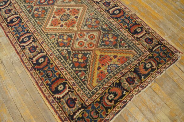 Dark blue and rust geometric patterned rug with medium pile displayed over distressed wood plank flooring.