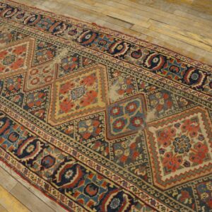 Distressed runner rug with blue and red geometric pattern and low pile on light wooden floorboards.
