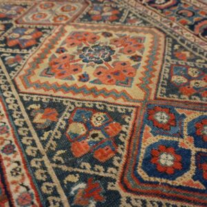 Detailed view of a rug with repeating geometric squares in navy blue, terracotta, and light tan.