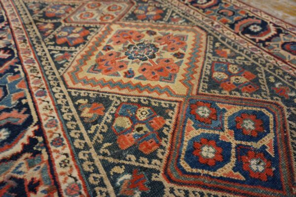 Detailed view of a rug with repeating geometric squares in navy blue, terracotta, and light tan.