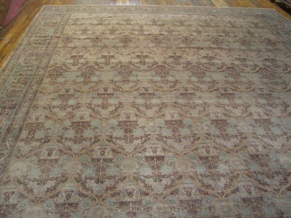 Large area rug featuring a faded botanical pattern in muted beige, blue, and brown on wood flooring.