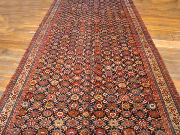 Long runner rug with a navy, red, and gold repeating geometric pattern on light wooden floors.