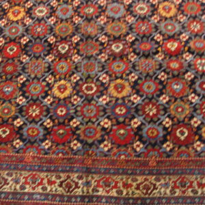 Multi-color rug featuring red, gold, and blue geometric medallions set on a dark blue lattice background.