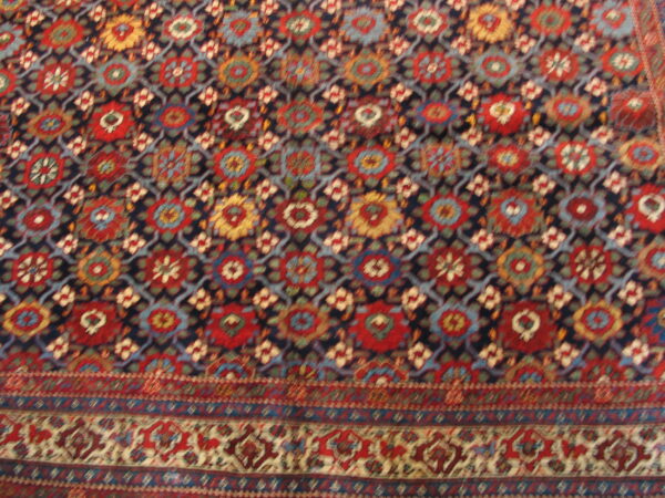Multi-color rug featuring red, gold, and blue geometric medallions set on a dark blue lattice background.