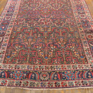 Intricate red, blue, and dark field rug with detailed borders rests on light wood floors.