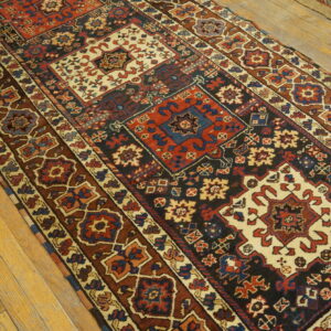 Geometric runner rug in deep red, dark blue, brown, and cream on light wood plank flooring.