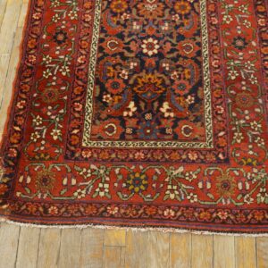 Traditional floral rug in red, navy, and cream on worn wood plank flooring.
